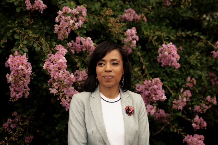 Angela Alsobrooks smiles for a portrait in front of a flowering bush