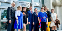 Parker Tirrell, third from left, and Iris Turmelle, sixth from left, pose with their families and attorneys outside of a courthouse