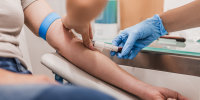 Close-up Of Doctor Taking Blood Sample From Patient's Arm in Hospital for Medical Testing.