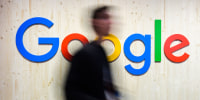 Trade fair visitors walk past a Google logo at the Google stand at Hannover Messe 2024.