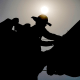 Image: A linesman works on power lines under the morning sun